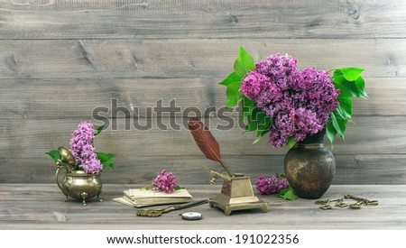 vintage still life with lilac flowers in vase on wooden background. retro style toned picture