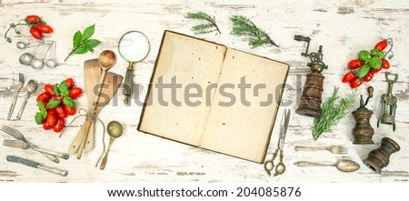 Vintage kitchen utensils with old cookbook, vegetables and herbs. Retro style toned picture