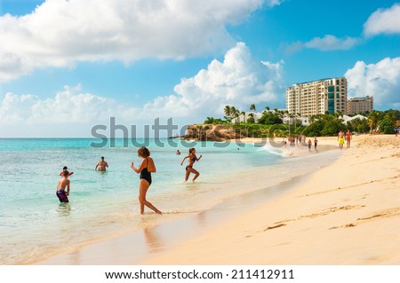 ST. MAARTEN, NETHERLANDS ANTILLES - JANUARY 1, 2014: People relaxing on Sunset Beach of Sint Maarten, Caribbean island of the Kingdom of the Netherlands, Netherlands Antilles