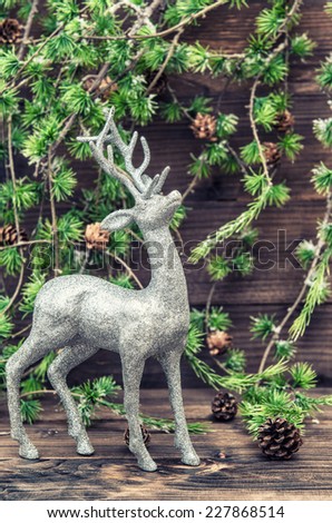 Christmas deer. Vintage style decoration with christmas tree branch on wooden background. Retro style toned picture