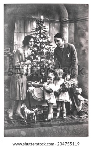 antique family portrait of parents and children with christmas tree. vintage picture with original film grain and blur. black and white photo