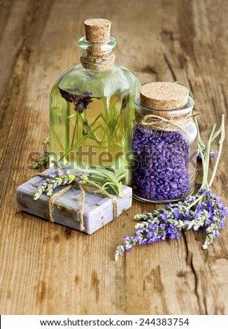 massage oil, herbal soap and bath salt with fresh lavender flowers on wooden background. selective focus