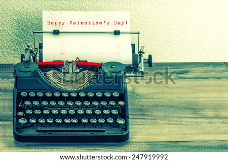 Typewriter with white paper page on wooden table. Sample text Happy Valentine\'s Day! Vintage style toned picture