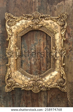Vintage golden frame on wooden background. Grunge wood texture. Selective focus on picture frame