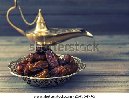 Dates and golden arabian lamp on wooden background. Oriental food. Retro style toned picture. Selective focus