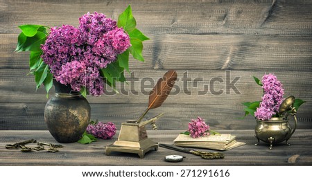 Still life with lilac flowers and antique writing tools on wooden background. retro style toned picture