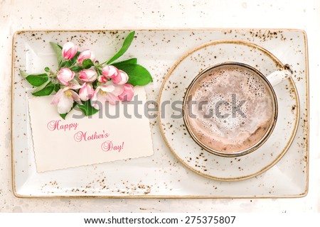 Hot chocolate with flowers and greetings card. Cocoa drink with milk foam. Happy Mother's Day!