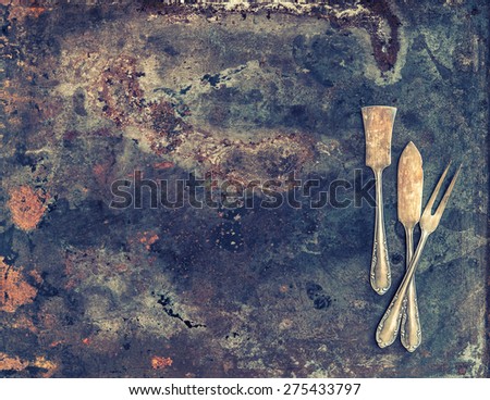 Antique silver cutlery on rustic textured metal background. Old tableware. Vintage style toned picture