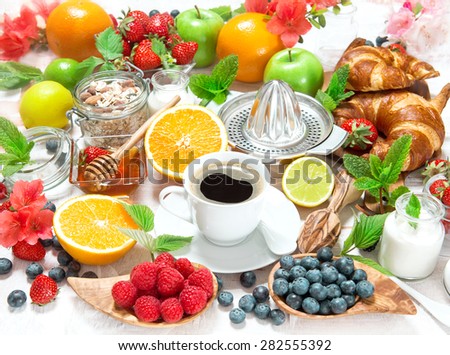 Breakfast coffee, croissants, cereal granola, honey, fresh berries, fruits orange, apple, milk. Healthy food concept