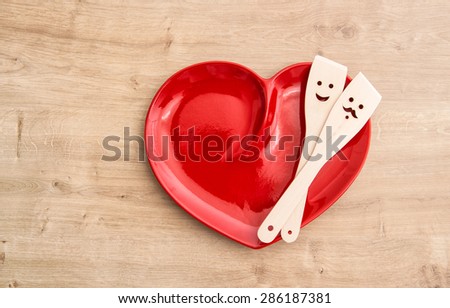 Wooden kitchen utensils on red hearth plate. Funny food background