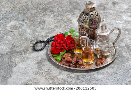 Tea and red rose flower, arabian lantern and rosary. Islamic holidays decoration. Ramadan kareem. Eid mubarak. Oriental hospitality concept.
