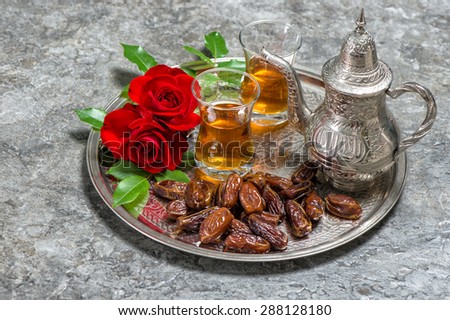Tea, dates fruits and red rose flowers. Islamic holidays decoration. Ramadan kareem. Eid mubarak. Oriental hospitality concept. Slective focus