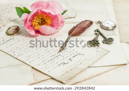 Old handwritings, antique feather pen, keys, pocket watch and pink peony flower. Sentimental vintage background. Selective focus