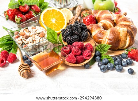 Breakfast with croissants, muesli, fresh berries, fruits orange, apple, milk. Healthy nutrition