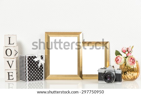 Golden picture frames, roses flowers and no name vintage camera. Retro style decorations with space for your photo