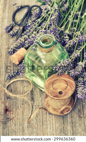 Lavender flowers bouquet with herbal oil and home tools on wooden background. Country style decorations. Retro toned photo