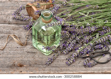 Herbal lavender oil with fresh flowers bouquet on wooden background. Vintage style still life