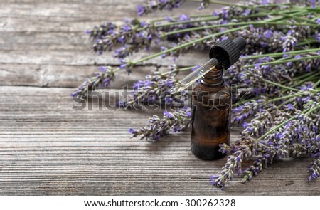Herbal oil and lavender flowers bouquet on wooden background. Alternative home medicine. Selective focus