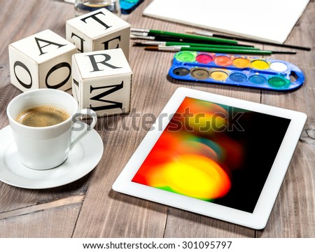 Artistic workplace mock up with black coffee. Watercolor, brushes, painting tools and accessories. Light leaks on tablet pc screen