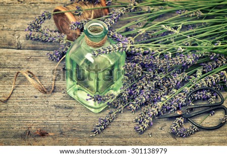 Herbal lavender oil with fresh flowers bouquet on wooden background. Country style still life. Vintage toned picture with vignette