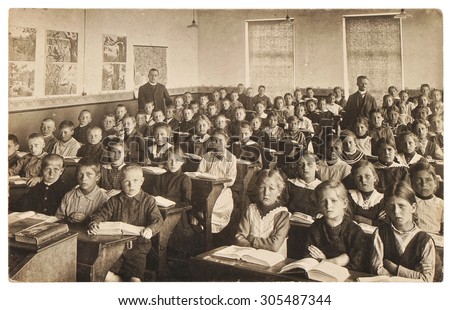 Retro picture of classmates. Group of children in the classroom. Vintage photo from 1920 with original film grain, blur and scratches.
