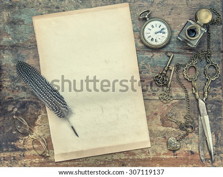 Letter paper and vintage writing tools. Feather pen, inkwell, keys on textured wooden background. Retro style toned picture