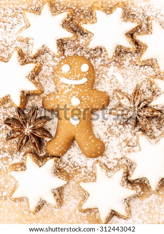 Christmas bakery. Gingerbread man cookie, cinnamon stars and star anise on wooden background with sugar powder