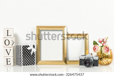 Golden picture frames, rose flowers and no name vintage photo camera. Retro style decorations