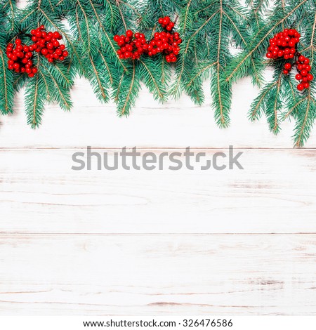 Christmas tree branch with red berries on wooden background. Winter holidays decoration. Retro style toned picture