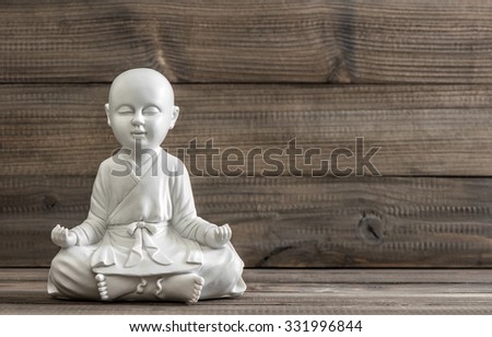 Sitting buddha. White statue on wooden background. Relaxing concept