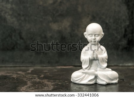 Buddha statue on dark background. Praying white monk. Meditation concept.  Vintage style toned picture