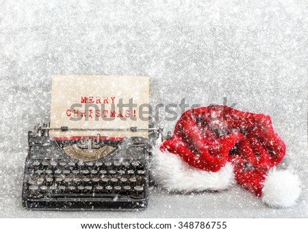 Old typewriter with red hat and sample text Merry Christmas. Retro style picture with falling snow effect
