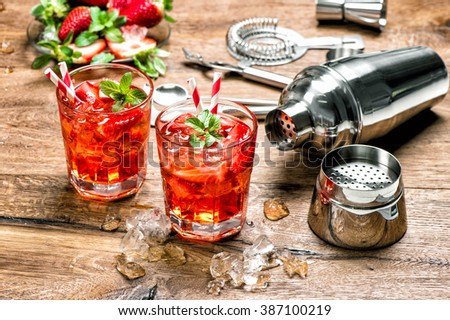 Red drink with ice. Cocktail making bar tools, strawberry and mint leaves