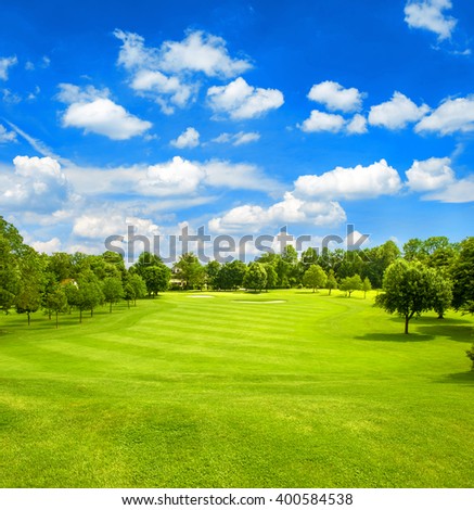 Green field and blue cloudy sky. Golf course. Fairway. European landscape