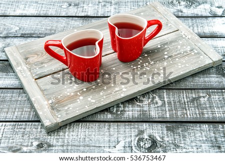 Heart shaped cups with red drink on rustic wooden background. Valentines day