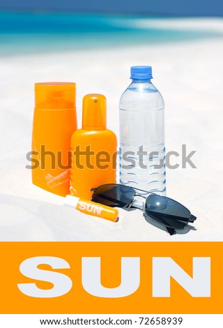 Sunglasses, water and sun protection cream on beach background