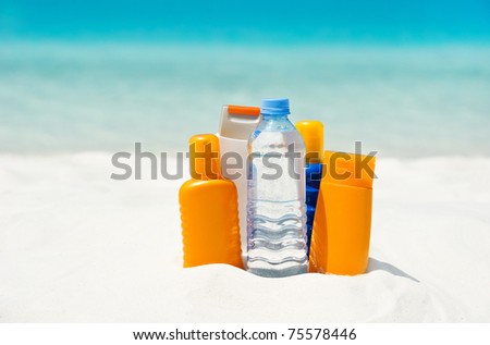 water and sun protection cream on beach background