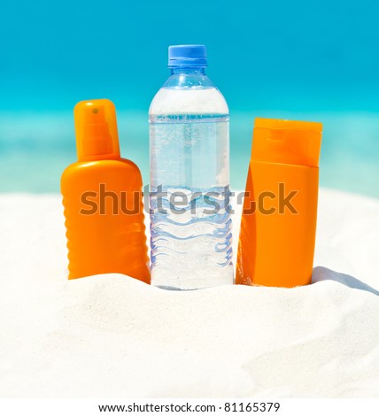 water and sun protection cream on sand beach background