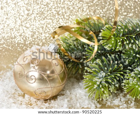 golden christmas ball with christmas tree branch. shiny golden background