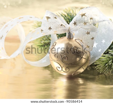 golden christmas ball with christmas tree branch. golden ribbon bow decoration.