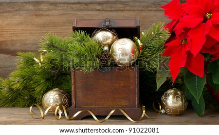 christmas tree brunch with golden decoration, vintage wooden box and red christmas flower poinsettia