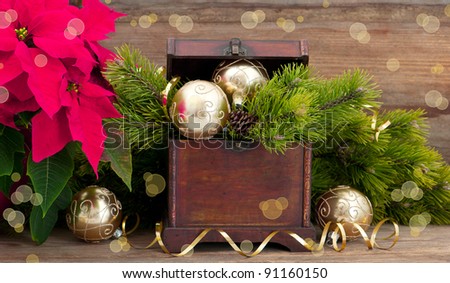 christmas tree brunch with golden decoration, vintage wooden box and pink christmas flower poinsettia
