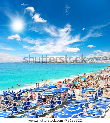 View of the beach in Nice, France, near the Promenade des Anglais, full with tourists, sunbeds and umbrellas on summer hot day