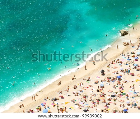 beach with tourists, sunbeds and umbrellas on the hot summer day