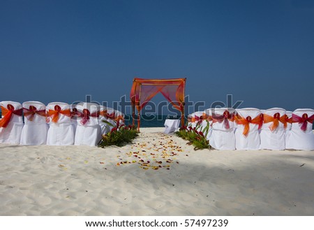 Beautiful beach scene set for a wedding ceremony with chairs, arbor, and flowers