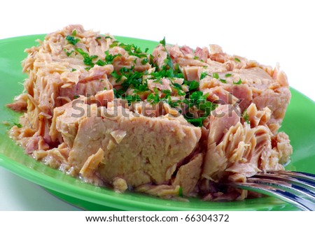 Tinned tuna with some parsley on a green plate isolated on white
