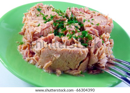 Tinned tuna with some parsley on a green plate isolated on white