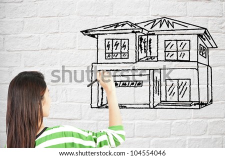 woman draw house on brick wall