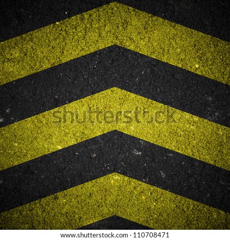 Yellow and black warning sign on asphalt texture