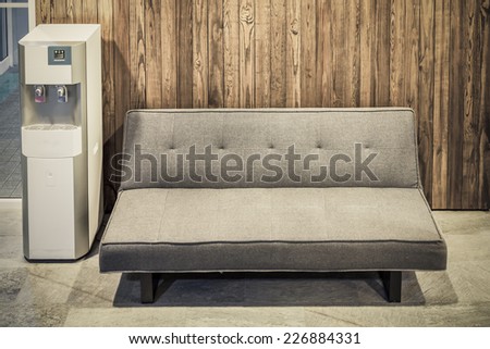 sofa furniture and water cooler on wood texture background